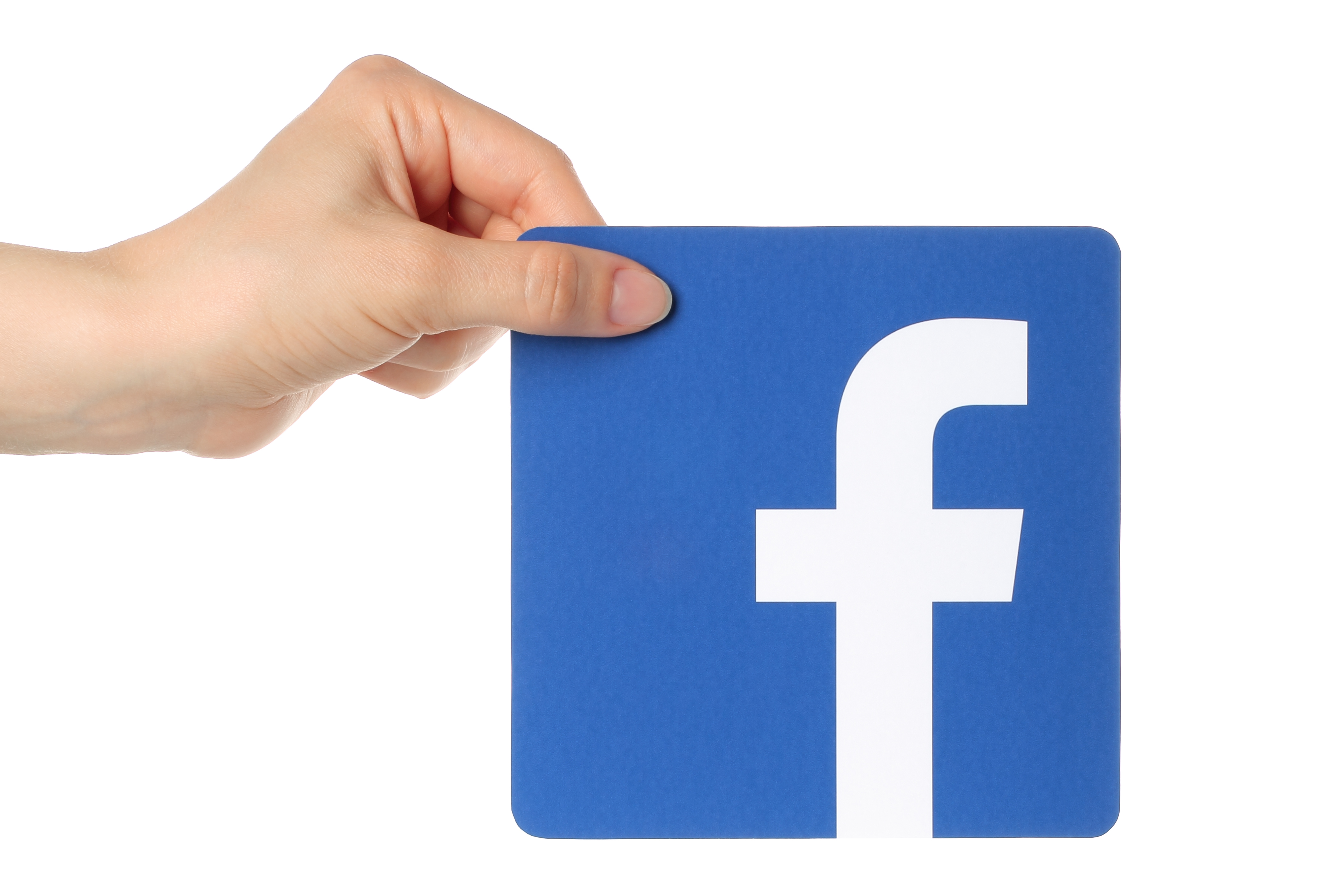 KIEV UKRAINE - APRIL 30 2015: Hand holds facebook logo printed on paper on white background. Facebook is a well-known social networking service.